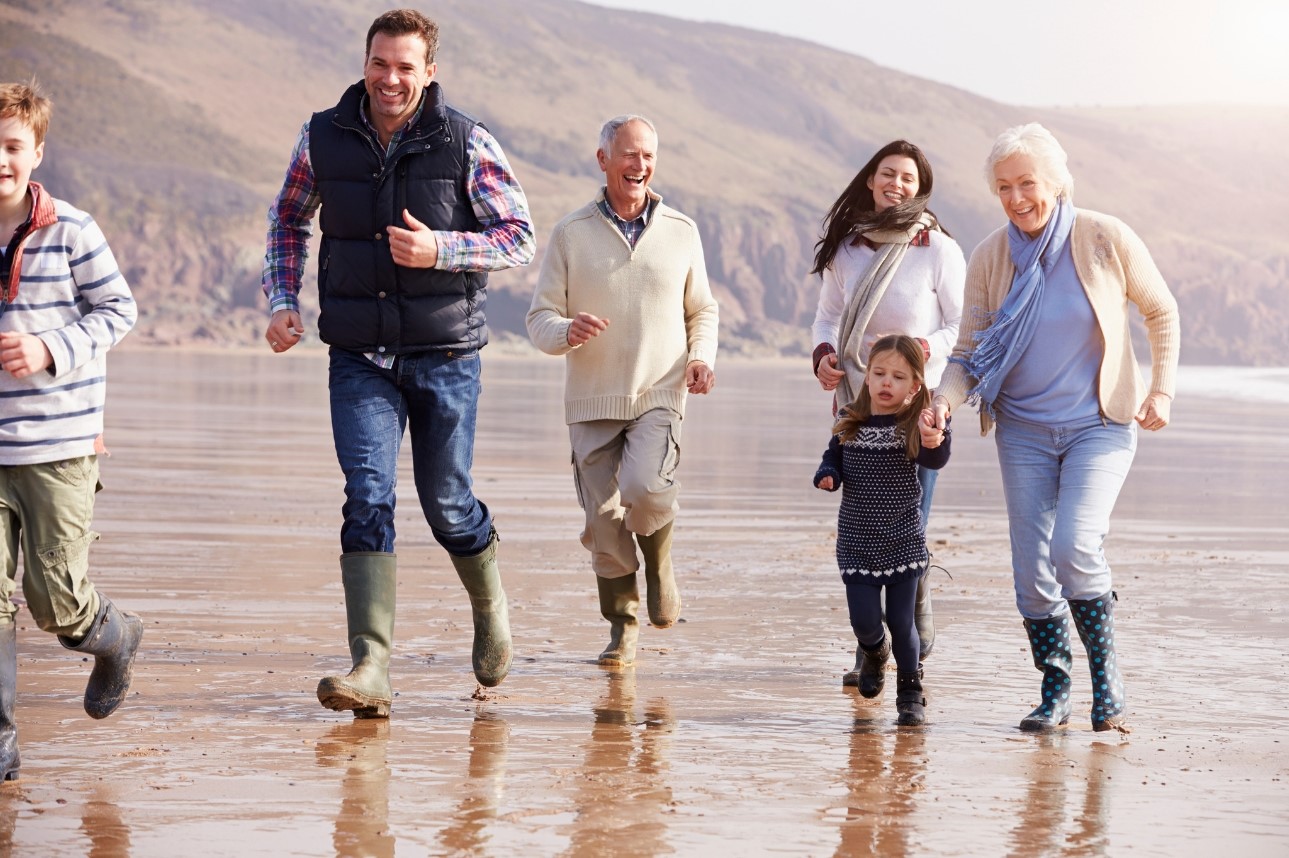 Multi-Generational Family Running Across The Beach