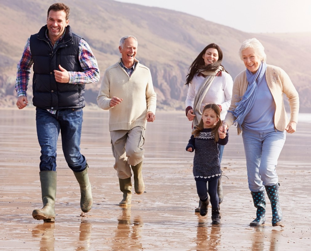 Multi Generational Family Running Across the Beach